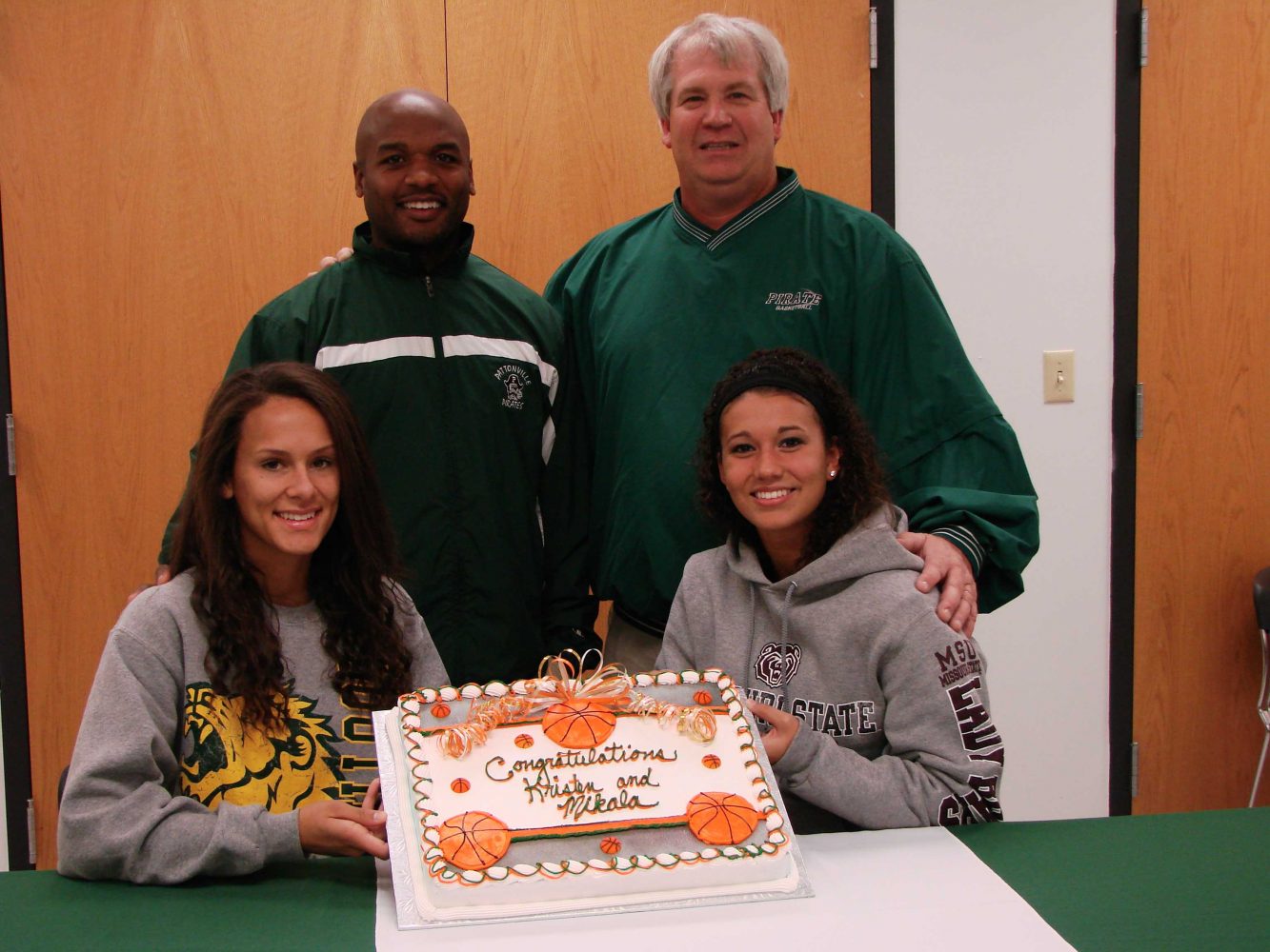Kristen Hanna and Mikala McGhee with their coaches after signing