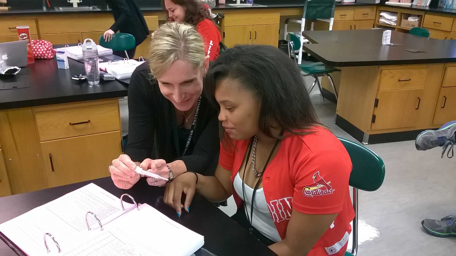 Stendeback helping one of her students read a thermometer. 