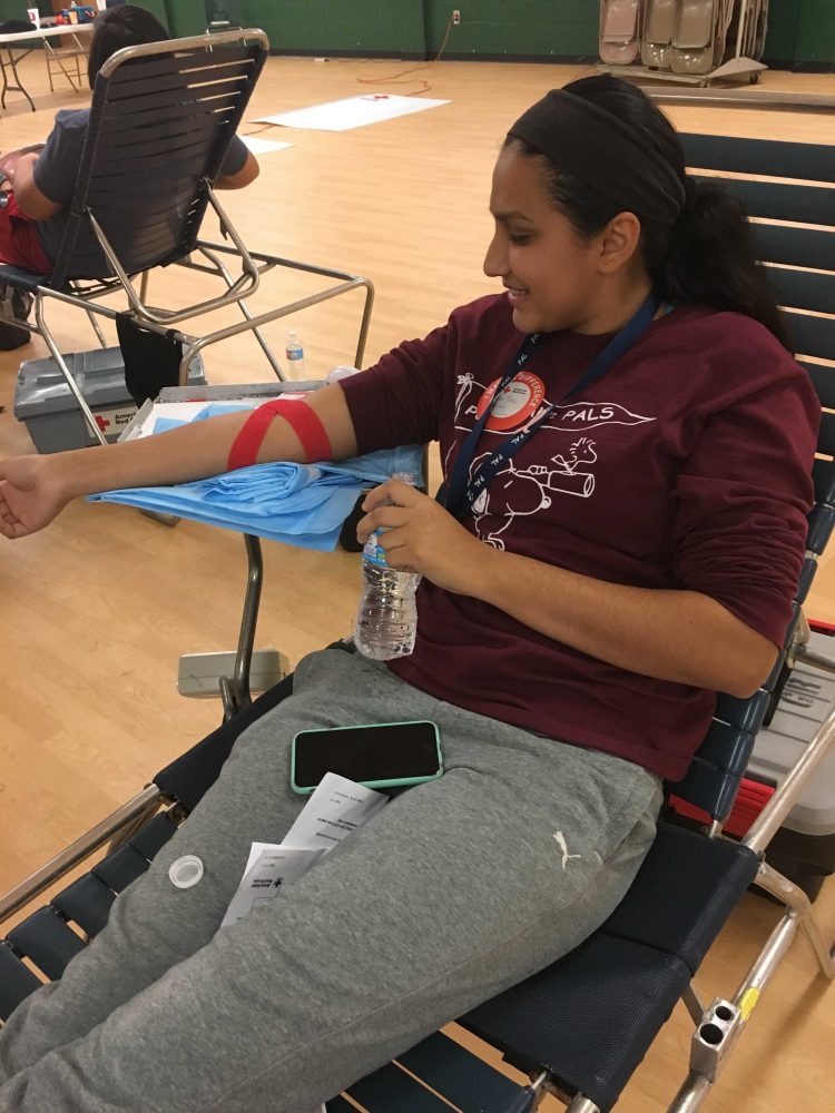 Senior, Roma Patel, drinking water after giving blood