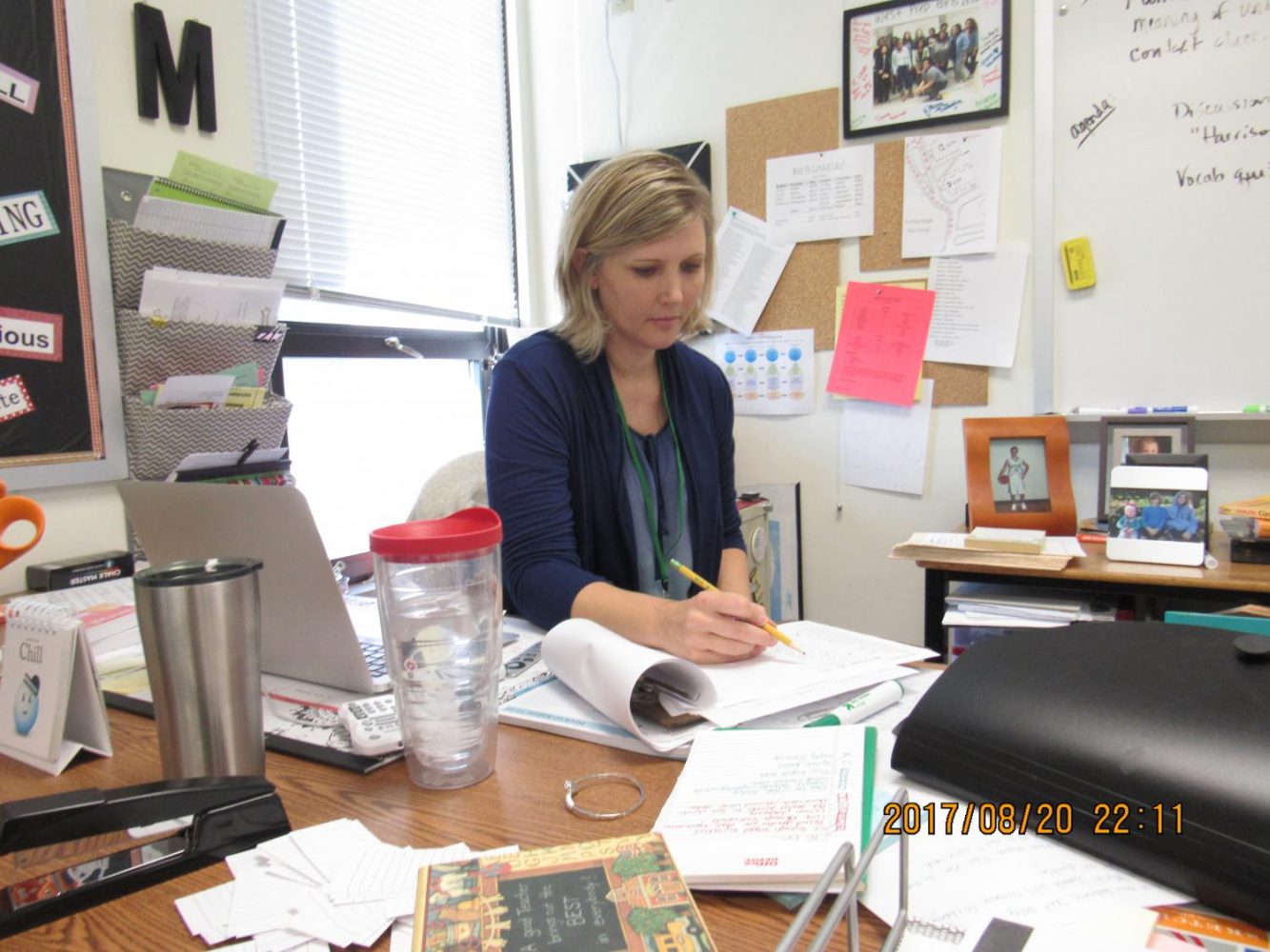 Mrs. Jodi Moeller sits at her desk taking roll for her students.