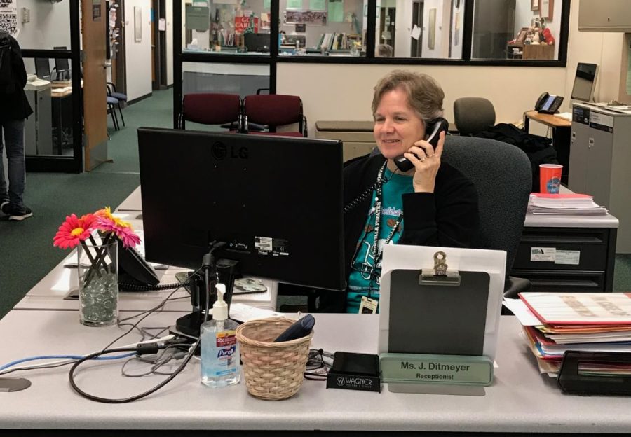 High school receptionist Ms. Jackie Ditmeyer takes a call from someone at her desk.