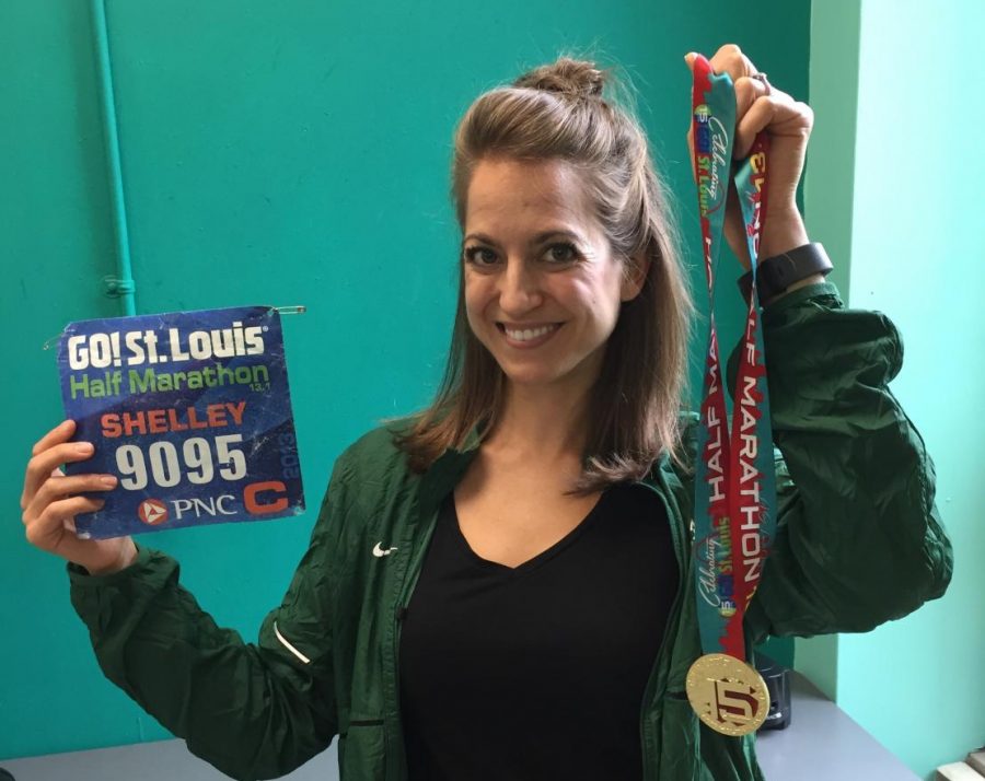 Ms. Shelley Christian holds her race bib and medal from the Go! St. Louis Half Marathon.