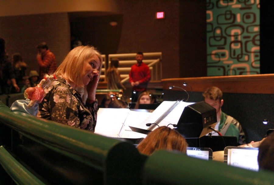 Ms. Sara Deutschmann wipes a tear away from her eye after she directs the orchestra pit during the musical for the final time. 