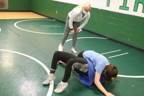 Coach Mueller explains a move at wrestling practice to Makiah Ashby and Analeah Robertson. This is their first year on the wrestling team.