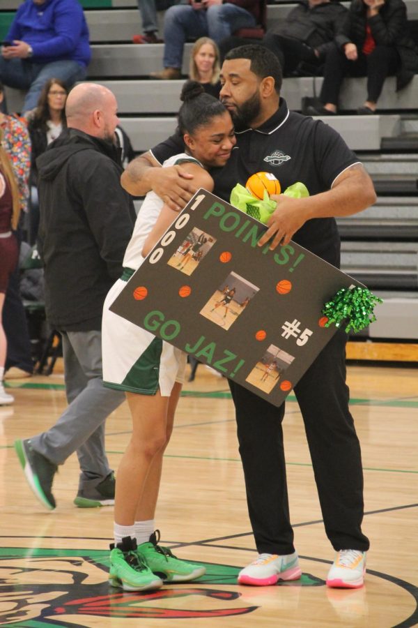 Coach Donald Boyce congratulates Senior Jasmine Gray with a hug and a poster made by her team.