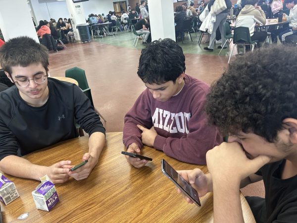 Freshmen Michael Saccketti, Thasin Kazi, and Mustafa Kareem scroll through their phones at lunch. 